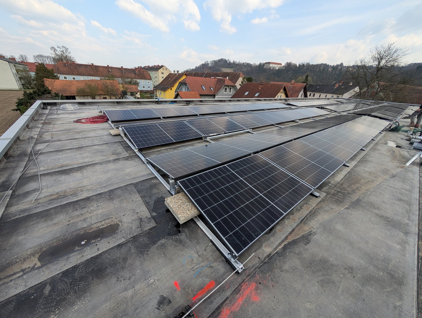 Aufgeständerte PV-Modulreihen auf einem Flachdach mit Blick über den Ort