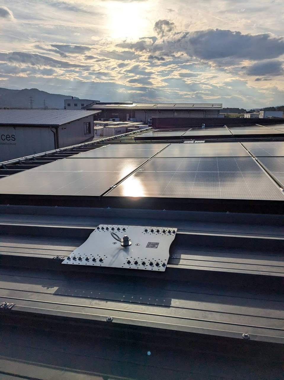 Anschlagpunkt auf dem Trapezblechdach vor der PV-Anlage im Abendlicht