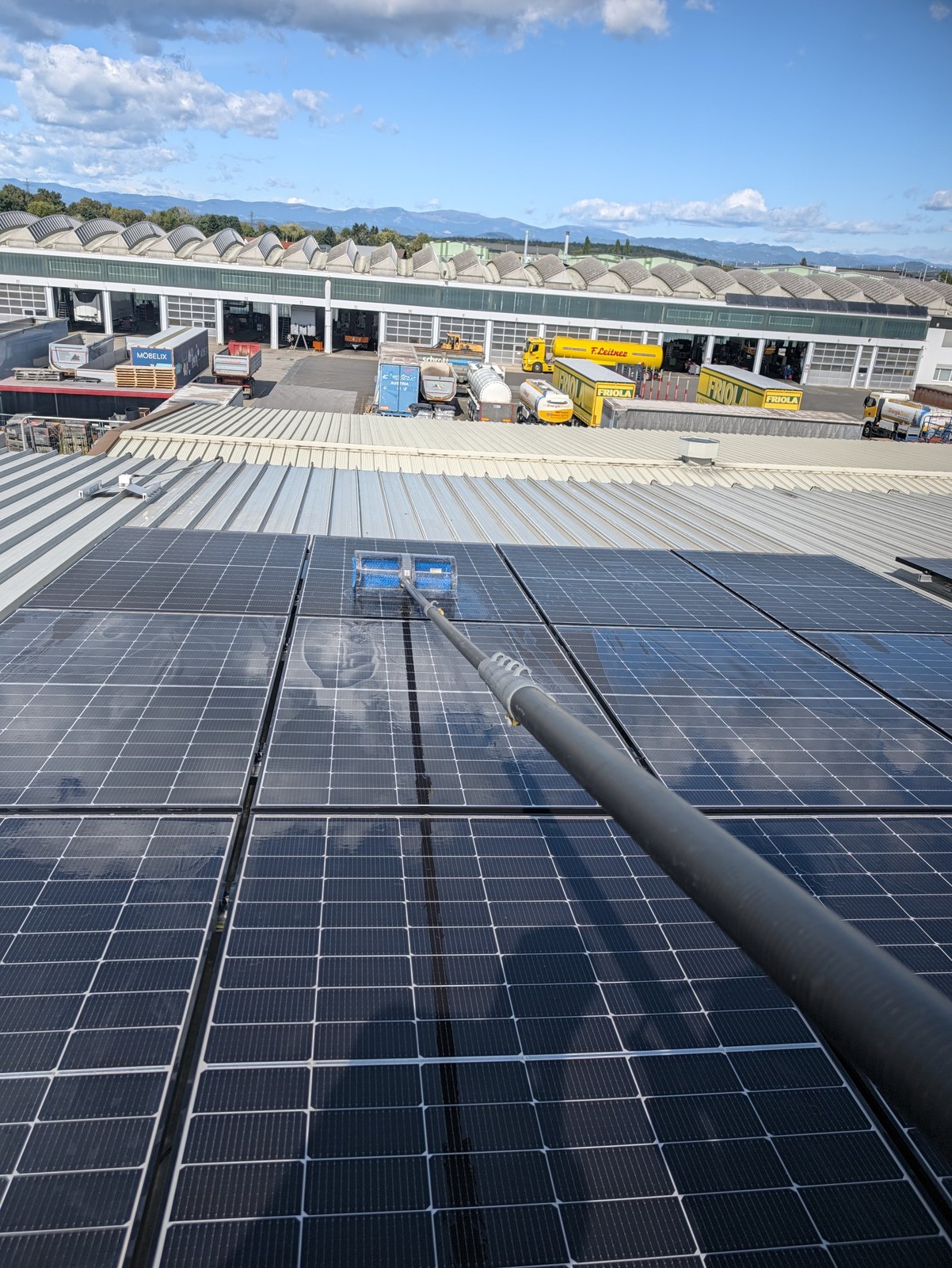 PV-Reinigung mit Teleskopstange und entmineralisiertem Wasser auf einem Gewerbedach