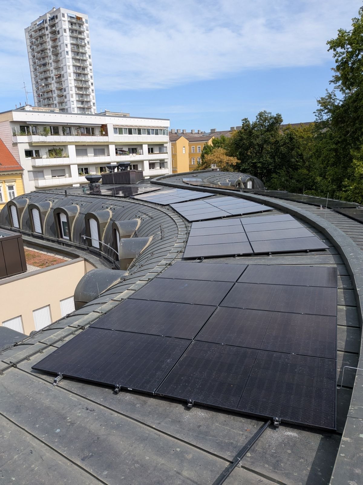 Fertiges PV-Modulfeld auf einem Tonnendach mit Stadtkulisse