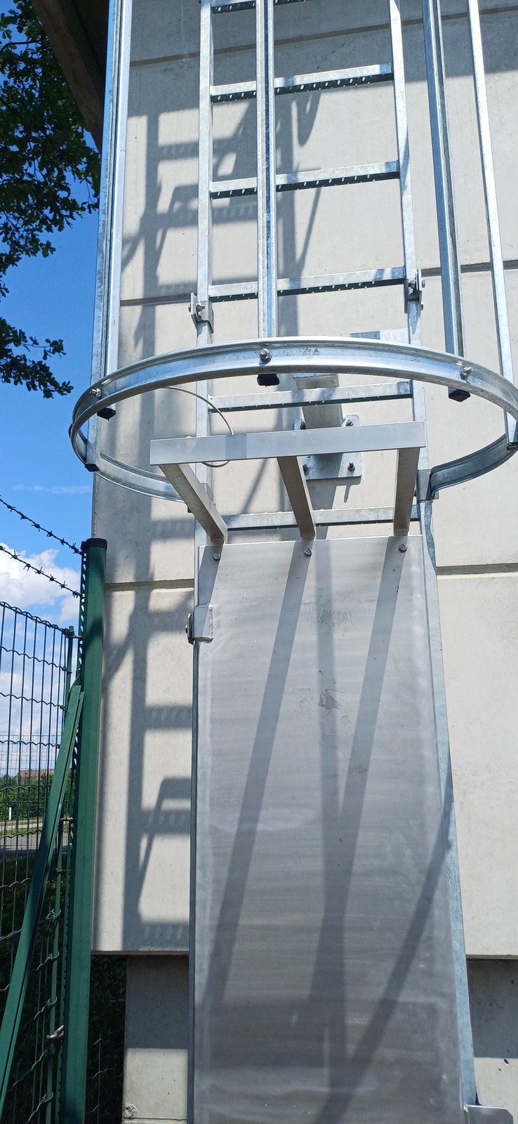 Steigleiter mit Rückenschutzkorb an einem Betonbauwerk